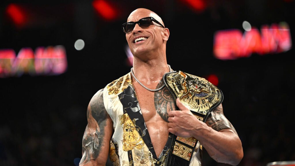 WWE superstar The Rock, wearing sunglasses and a stylish vest, smiles while holding a championship belt on WWE Raw news
