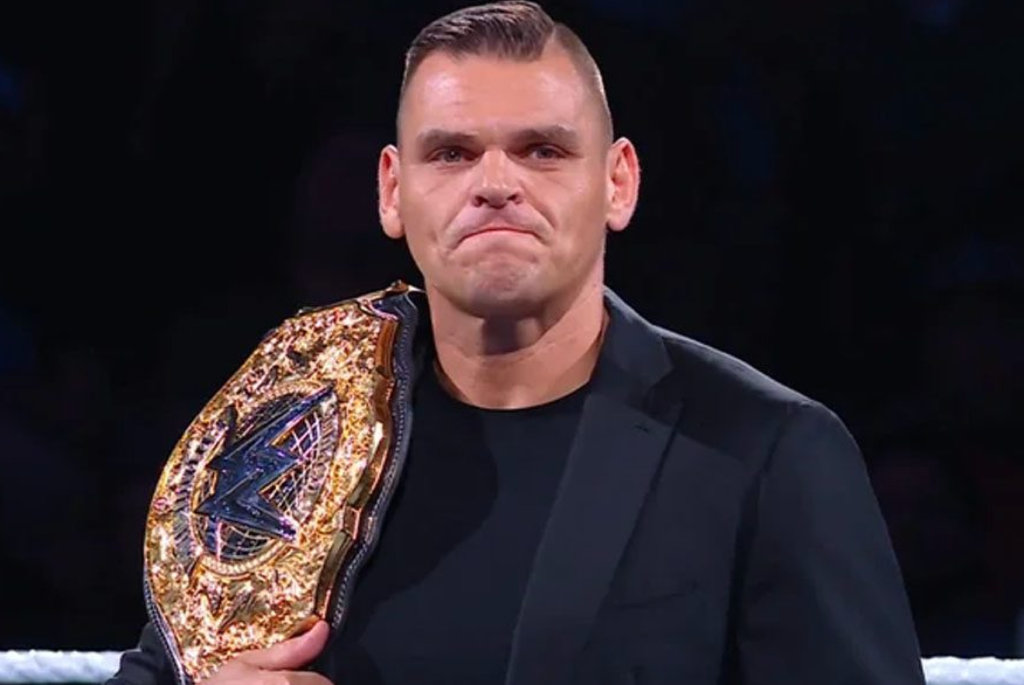 Gunther in a black suit holding the WWE raw news championship belt