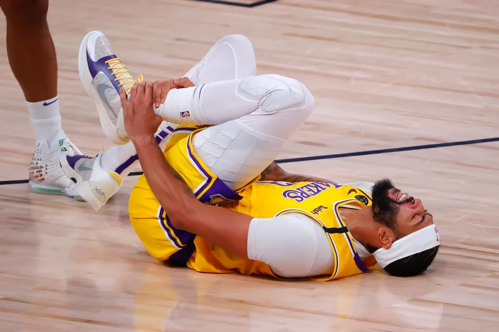 Anthony Davis grimaces in pain while holding his left thigh after an awkward landing during a game against the Houston Rockets.