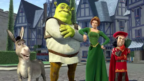 Shrek, Fiona, and their three children sitting together near a fireplace in their swamp house.