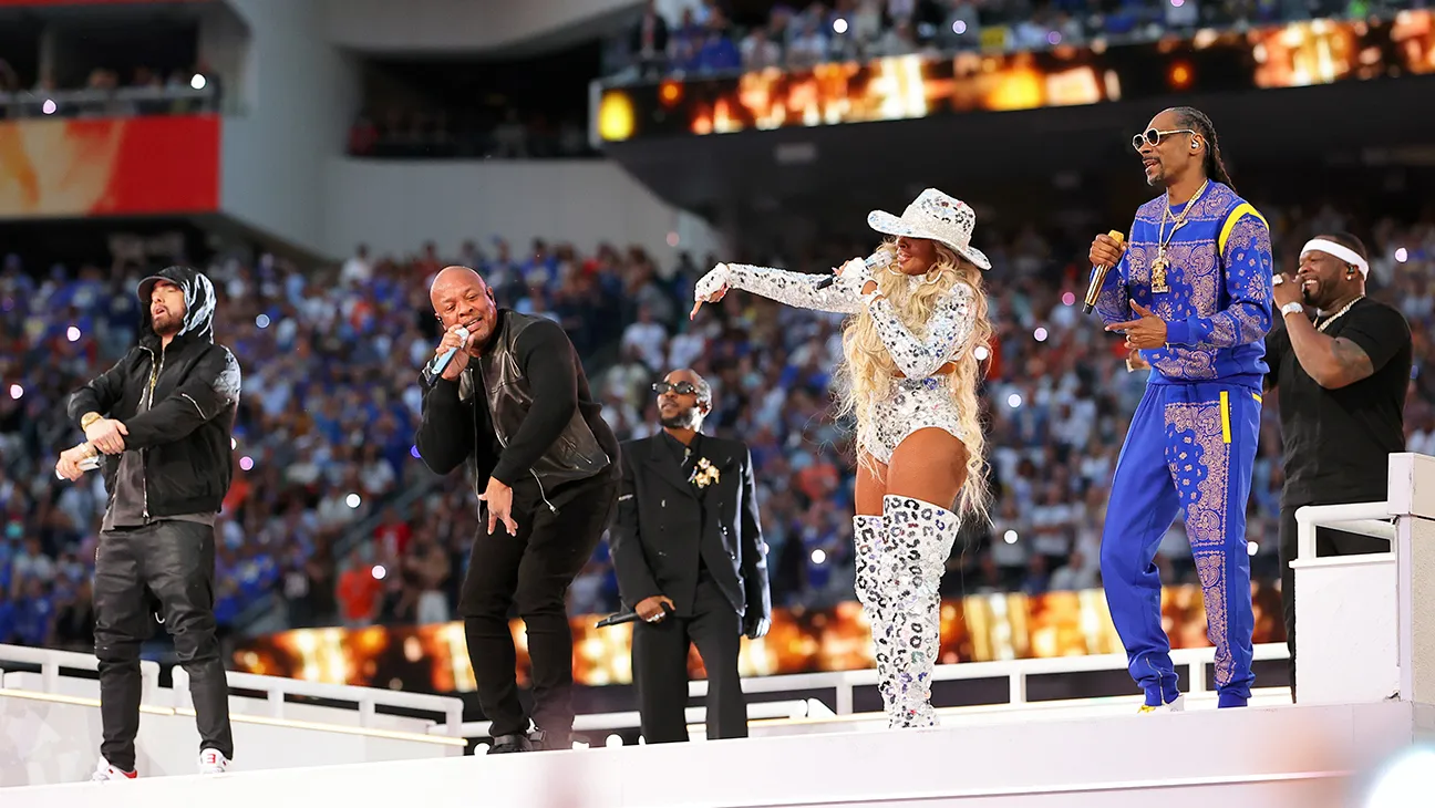 Performer on stage during the Super Bowl halftime show, surrounded by bright, colorful lights.