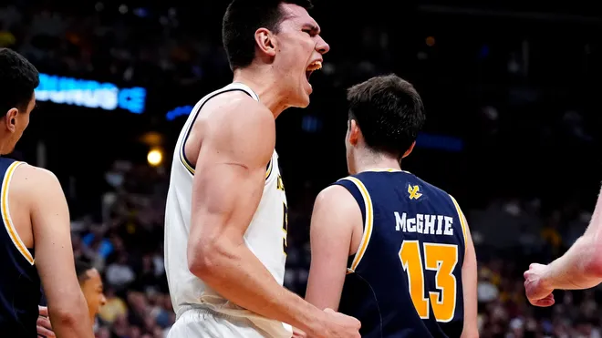 Michigan basketball players celebrating an overtime win in the NCAA Tournament 2025.