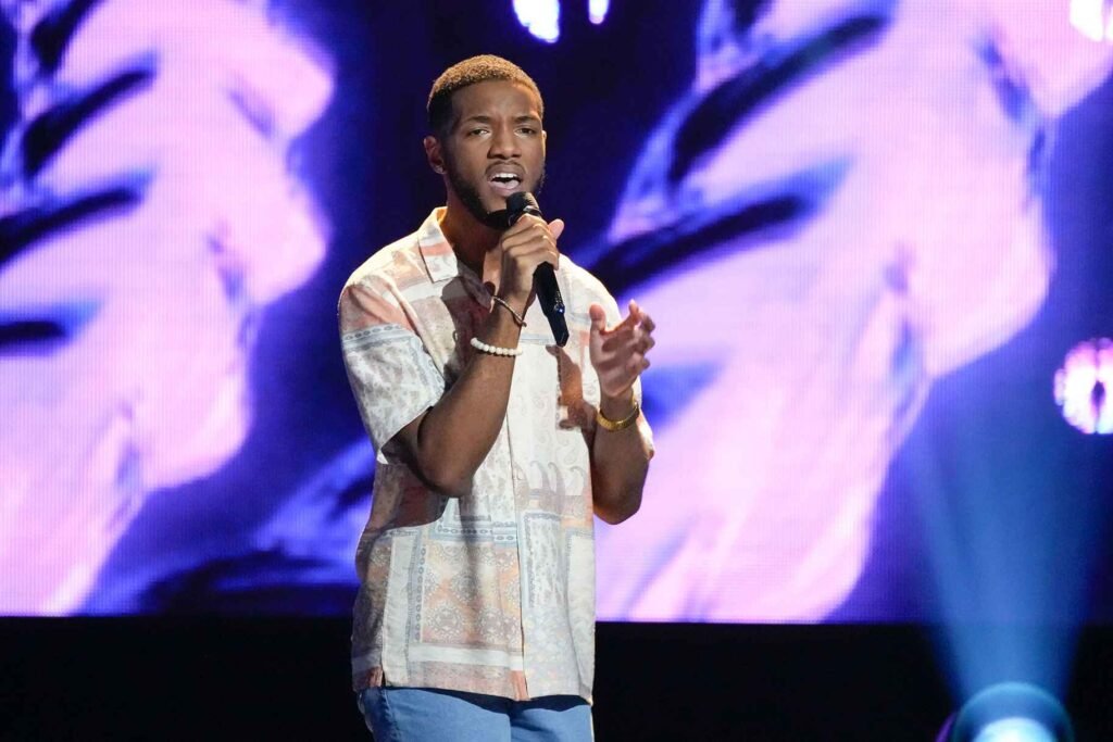 A contestant performing in front of a live audience with bright stage lights.