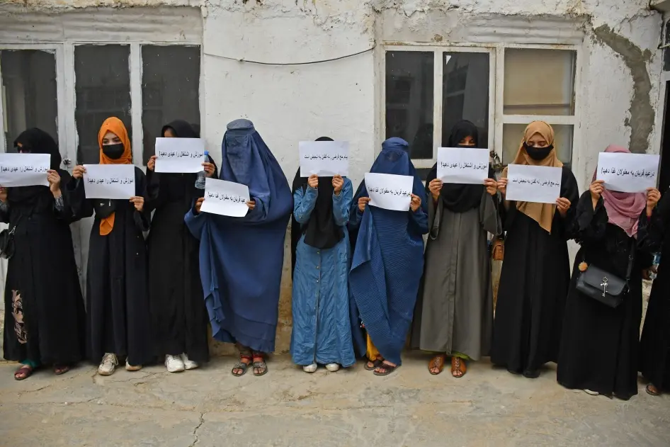 Afghan women holding protest signs demanding rights under Taliban rule