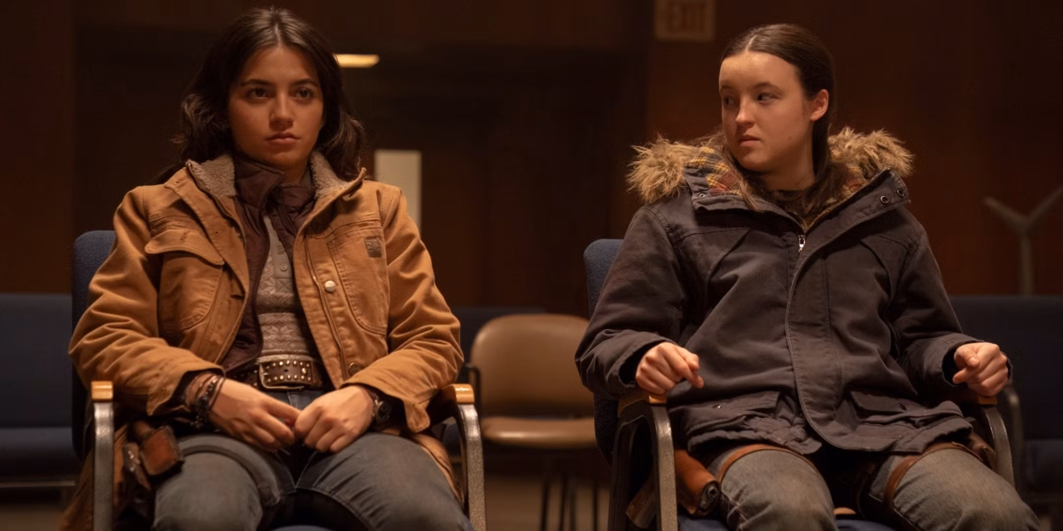 Ellie and Dina sitting close in a dimly lit room, sharing a quiet, emotional moment.